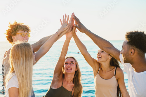 Happy group of friends raising their hands to the blue sky