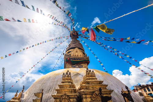 Nepal. Golden Stupa Bouddanath in Kathmandu with colorful Tibetan prayer flags, close-up on a sunny day. Was built in the 14th century. Blue cloudy sky in the background. Travel, holidays, sight