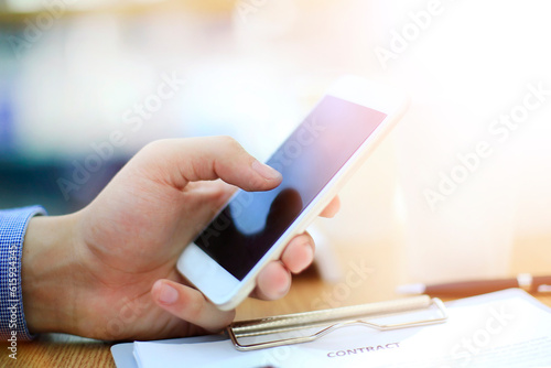 Close up of a man using mobile smart phone in modern office