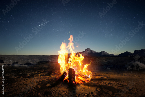 Exploring the wilderness in summer. A glowing camp fire at dusk providing comfort and light to appreciate nature, good times and the night sky full of stars. Photo composite.