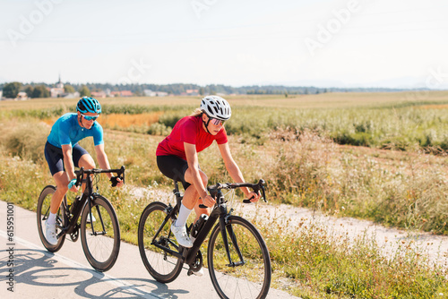 Two Caucasian athletes, female and male road racing cyclists, riding one after another