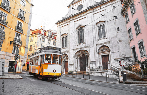Lisbon, Portugal. Vintage yellow retro tram on narrow bystreet tramline in Alfama district of old town. Popular touristic attraction of Lisboa city.