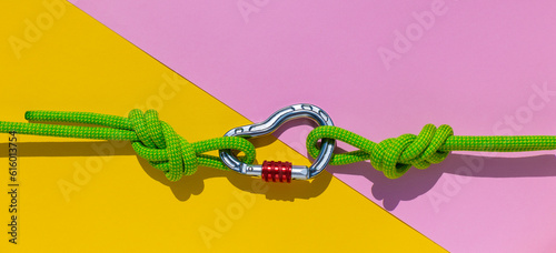 carabiner with a rope lies on a colored background. Equipment for climbing and mountaineering. reliable connection. Safety rope. Node eight. the concept of reliability and strength.