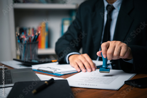 Hand man stamping documents notary public in office . Businessperson stamping approval of work finance banking or investment marketing documents on desk.