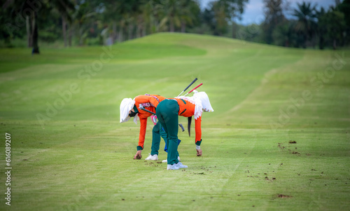 Caddies working at golf course by clear hole on green grass after finish golfer teeing in compettion game. 