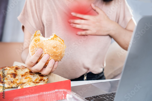 woman suffering from acid reflux , heartburn after over eating junk food, pizza and burger