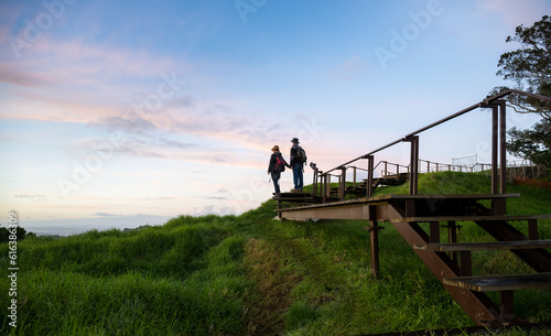 Couple standing on raised boardwalk around the crater at sunrise. Mt Eden Summit. Auckland.