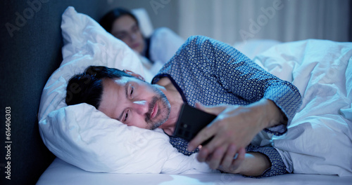 Young Man Using Cellphone While Her Wife Sitting On Bed