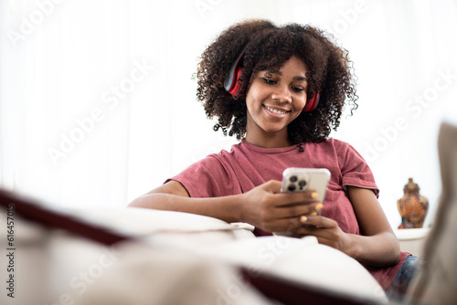 African American woman using the smartphone and listening musics on the sofa