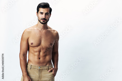 Male fashion model with a naked torso and abs packs sporty runs on a white isolated background, fashionable clothing style, copy space, space for text