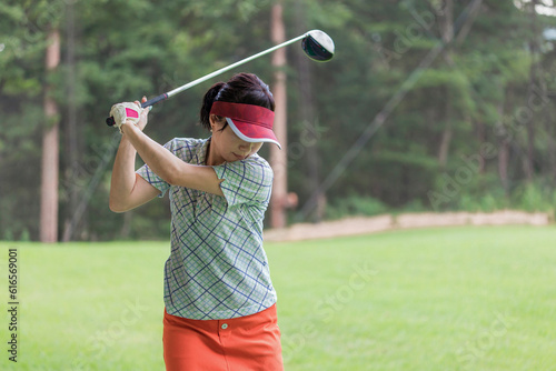 ゴルフ練習場・打ちっぱなし・ゴルフセンターでスイングの練習するゴルフ選手・ゴルファーの女性 