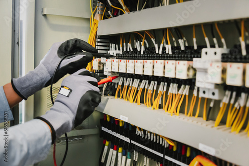 Electrical engineers test electrical installations and wiring on protective relays, measuring them with a multimeter.