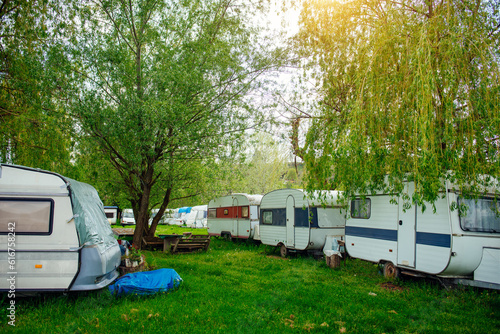 Caravan trailer on a green lawn in a camping site. Sunny day. Spring landscape. Europe. Lifestyle, travel, ecotourism, road trip, journey, vacations, recreation, transportation, RV, motorhome