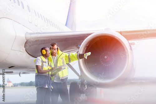 Air traffic control ground crew workers talking near airplane on airport tarmac