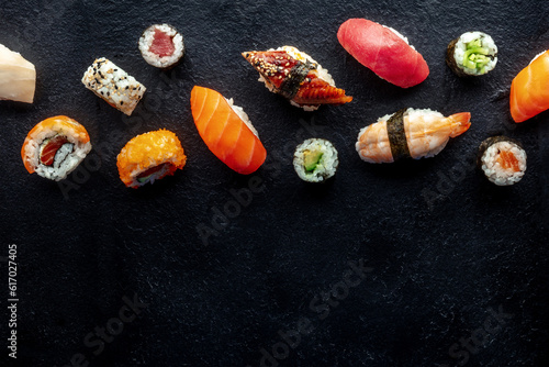 Sushi, shot from the top. Rolls, maki, nigiri on a black slate background, Japanese food. Salmon, eel, shrimp, tuna etc with rice, with a place for text
