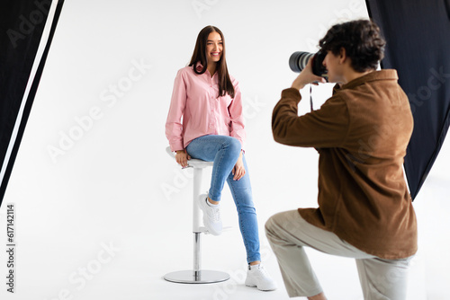 Stylish photoshoot. Male fashion photographer taking picture of young european woman in casual wear