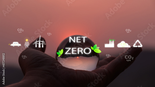 Environment concept. Hand holding glass ball with zet zero icon against morning . environmental icons. Global warming. Sustainable development. Solar , Green Business Future Sustainability Net Zero.