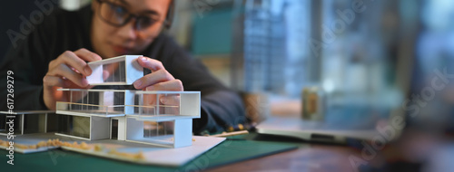 Architecture students diligently make house model building samples with paper architecture and tools at night in their alone room.