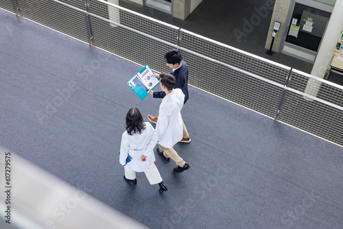 A multinational group having a conversation in the lobby. People in white coats and sales staff. High angle view.