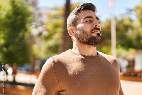 Young hispanic man smiling confident breathing at park