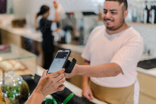 atendente recebendo pagamento por aproximação com o celular em umacafeteria no Brasil