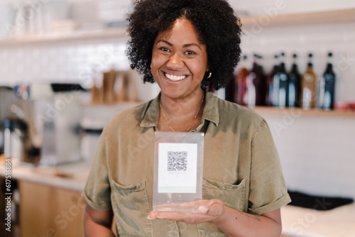 atendente de uma cafeteria no Brasil sorrindo segurando uma placa com um código QR impresso