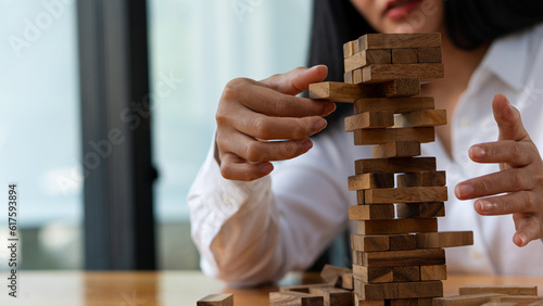 Young woman placing wooden blocks on tower, business plan and strategy, risk concept to grow business with jengka wooden blocks