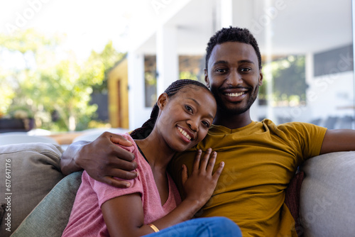 Portrait of happy african american couple smiling and embracing on couch at home