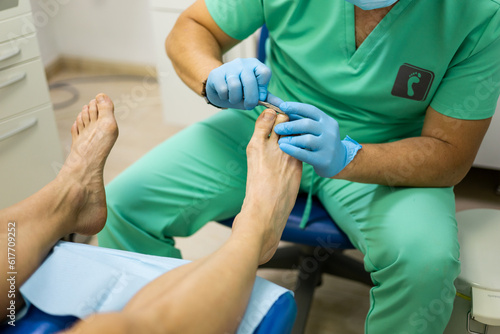 An unrecognizable podiatrist cuts the toenails during the pedicure procedure. Professional pedicure in the beauty salon. The beautician cuts the skin with his nails and performs professional pedicure.