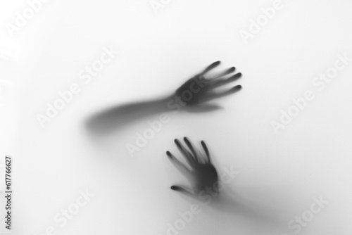 Defocused hand silhouette behind frosted glass in black and white mode, halloween concept