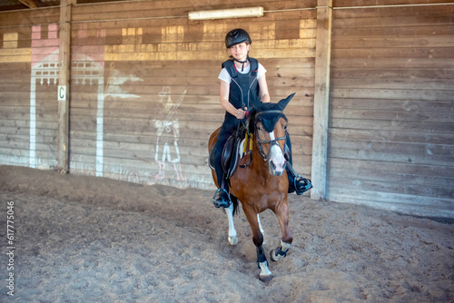 Beautiful young rider with green eyes galloping during her riding lesson