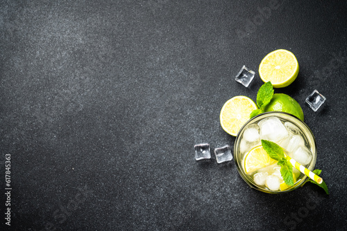 Mojito with rum, lime, mint and ice on black background. Traditional Summer drink. Flat lay.