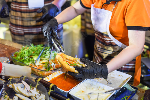 Vietnamese woman serving traditional vietnamese sandwich banh mi in street food at night