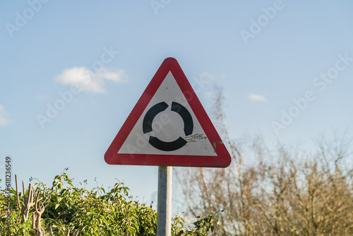 Triangle UK roundabout sign against blue sky with clouds, information, travel and tourism concept illustration.