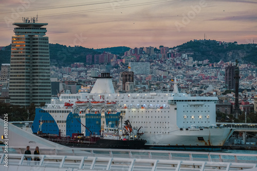 Passenger freighter roll on roll off ro-ro pax ferries in port of Barcelona, Spain with city skyline, yachts, marine vessels and harbor infrastructure