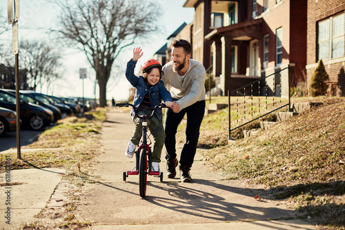 Father teaching his son how to ride a bike in the suburbs