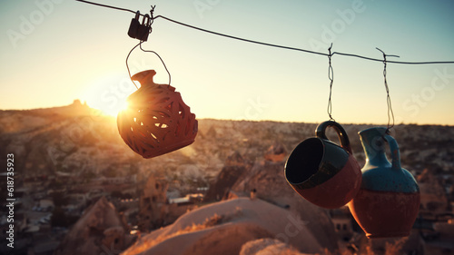 Row of clay jugs hanging on a wire opposite sunset in Cappadocia. Traditional turkish pottery