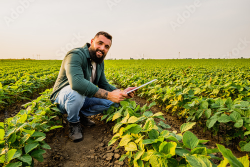 Portrait of farmer who is cultivating soybean. He is satisfied with good progress of plants. Agricultural occupation.