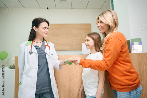 Mother shaking hand to pediatrician of her little daughter