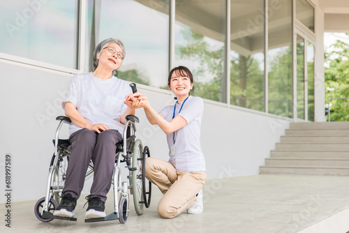 病院・介護施設で散歩する車椅子に乗った高齢者と介護士（ヘルパー・理学療法士） 