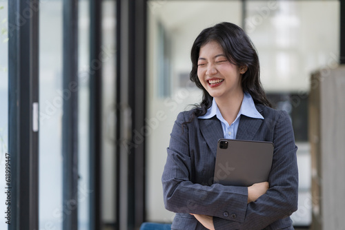 Beautiful Asian businesswoman standing and holding a digital tablet.