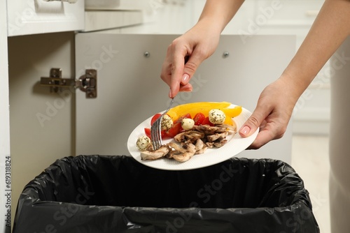 Woman throwing vegetable and mushrooms into bin indoors, closeup