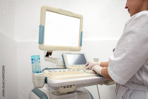 woman doctor in uniform uses a modern ultrasound machine with a blank screen, girl nurse works on medical equipment