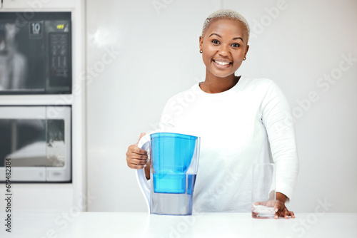 Water, filter and pitcher for woman in kitchen to refresh with glass of liquid hydration. Portrait, happy black female person or jug of pure aqua beverage for drinking cold or clean nutrition at home