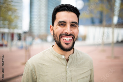 Cheerful young arabic man smiling outside in the city