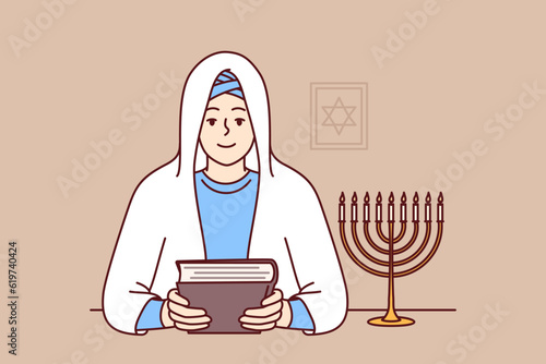 Jewish woman rabbi holds torah in hands and sits near image of star of david, dressed in religious clothes and white veil. Smiling girl learning jewish religion and prayers to worship god