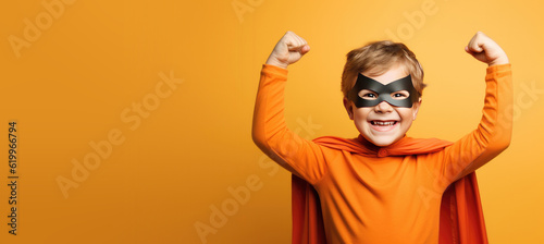 Cute Young Boy Dressed as a Superhero for Halloween on an Orange Banner with Space for Copy