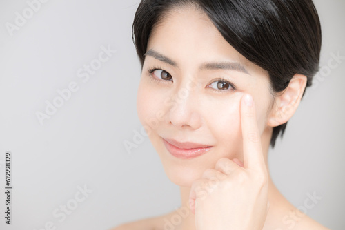 美容などに使いやすい睫毛や目元を指さすアジア系（日本人）女性のアップ カメラ目線