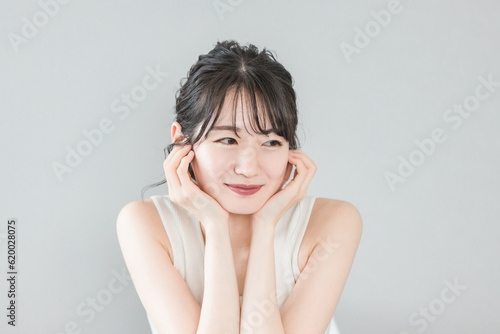 頬杖をつく美肌の笑顔のアジア人女性（美容・エステ・スキンケアイメージ） 