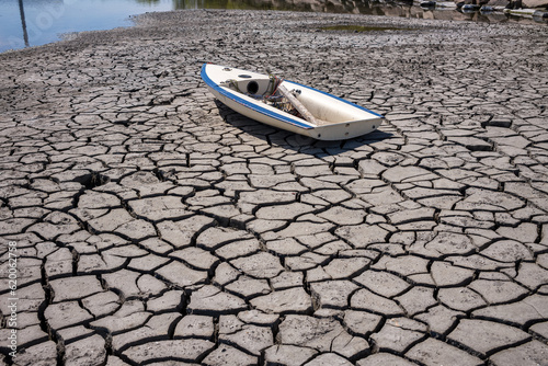 Boat on a dried up riverbed with cracked surface. Dry landscape caused by global warming.